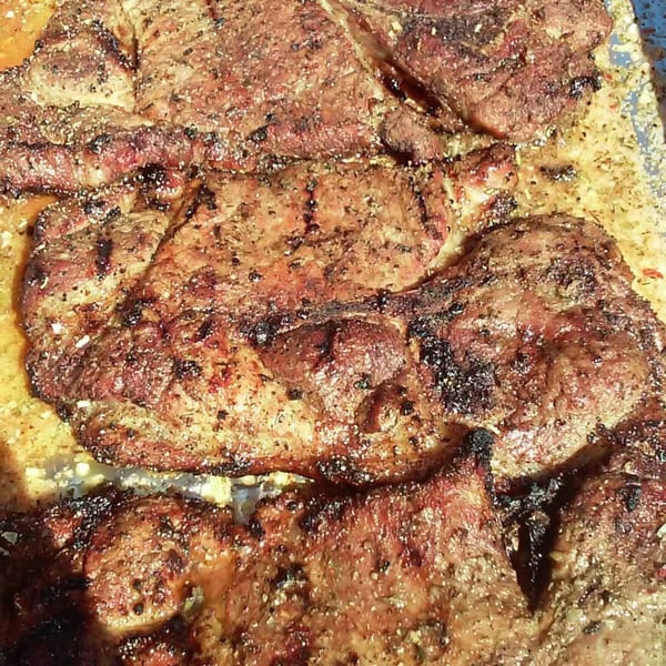 Close-up of several seasoned, grilled Five Ace's Smokestaq Lightning BBQ steaks with char marks.