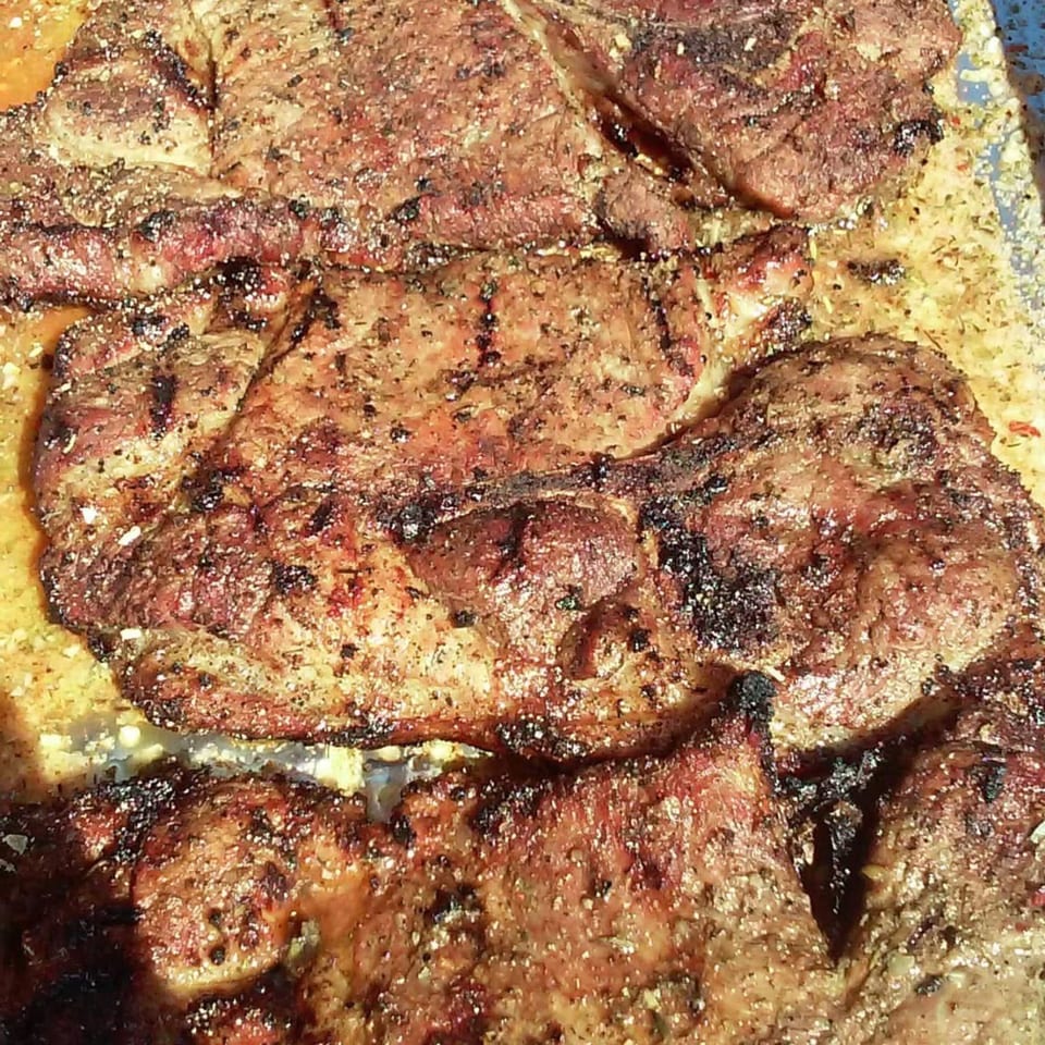 Close-up of several seasoned, grilled Five Ace's Smokestaq Lightning BBQ steaks with char marks.