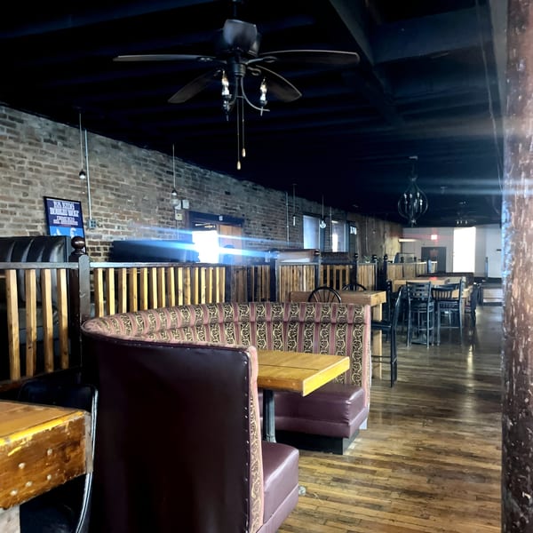 Interior of Five Ace's Smokestaq Lightning with booth seating, wooden tables, and brick walls.
