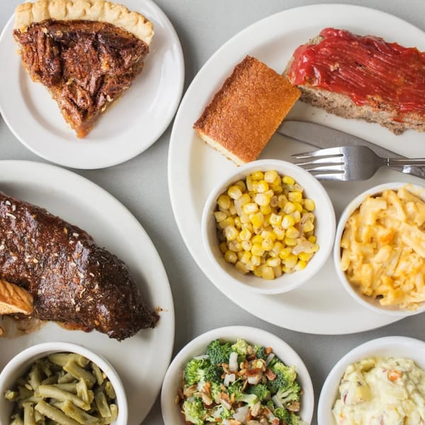 A spread of Five Ace's Smokestaq Lightning BBQ dishes, including ribs, meatloaf, pecan pie, and various sides.