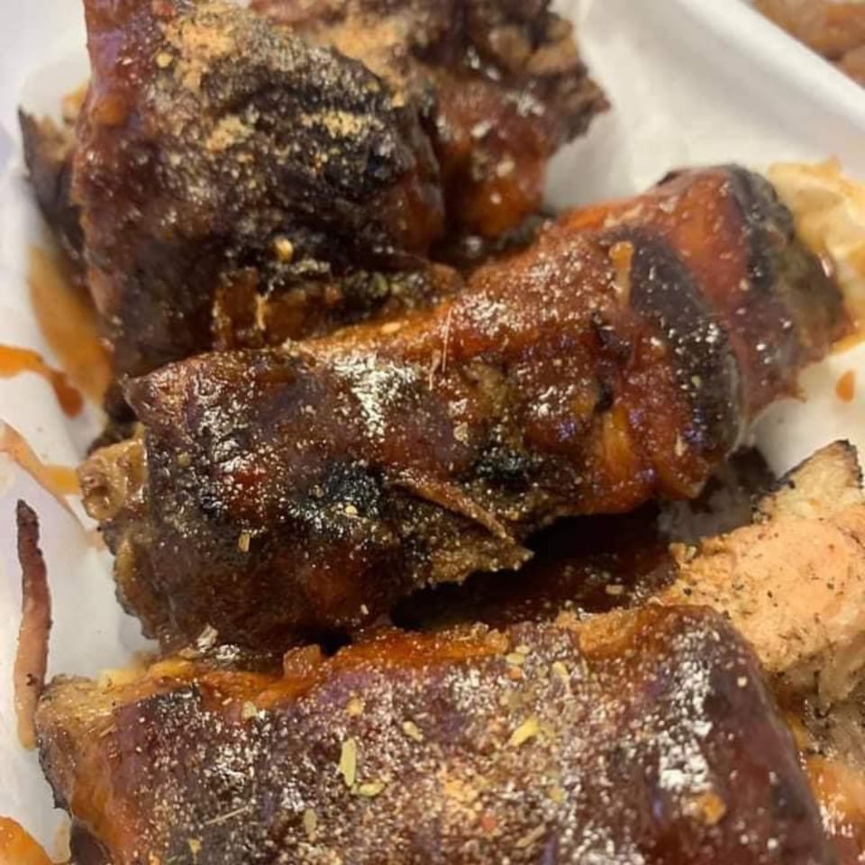 Close-up of Five Ace's Smokestaq Lightning BBQ ribs, glistening with sauce and sprinkled with seasoning.