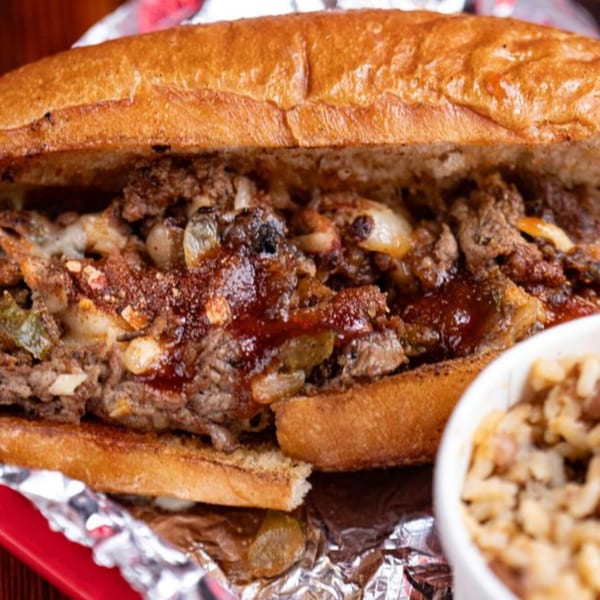 A Five Ace's Smokestaq Lightning BBQ cheesesteak with onions, peppers, and sauce, served with mac and cheese.