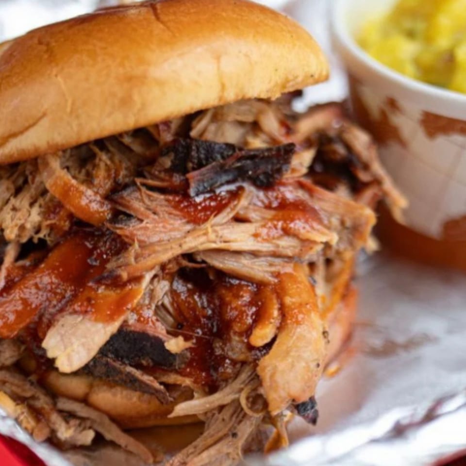 Close-up of a Five Ace's Smokestaq Lightning pulled pork sandwich with a side of mac and cheese.